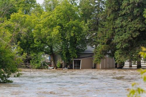 The Swan River overflows its banks, flooding nearby homes in Swan River on July 2. (Mike Deal / Free Press files)