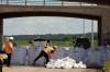 Tim Smith/The Brandon Sun
                                Workers install super sandbags to block off access to Grand Valley Road at the Trans Canada Highway overpass on Wednesday as part of flood preparations.