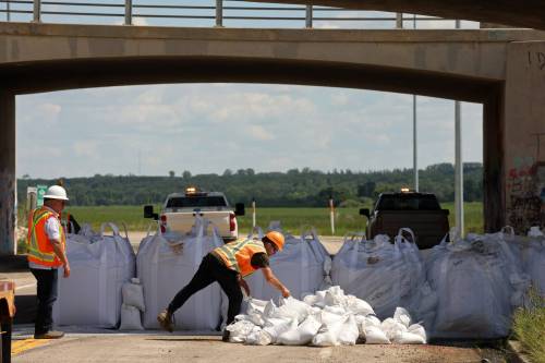 Tim Smith/The Brandon Sun
                                Workers install super sandbags to block off access to Grand Valley Road at the Trans Canada Highway overpass on Wednesday as part of flood preparations.