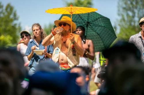 BROOK JONES / FREE PRESS
                                Folk Fest attendee Jayme Halbritter, 34, from Minneapolis, Minn., takes a sip of water while holding a parasol to try to keep cool on an extremely hot summer day while Yagódy performs on the Snowberry Field Stage at the Winnipeg Folk Festival at Birds Hill Provincial Park on Sunday.