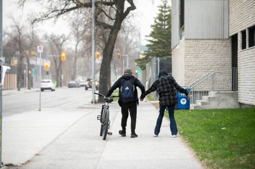 MIKAELA MACKENZIE / FREE PRESS FILES
                                A woman who was in distress is helped along Maryland Street near Gordon Bell High School in May.
