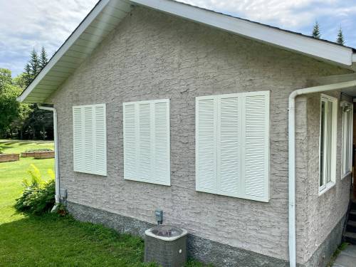 Three sets of three faux window shutters cleverly conceal the old abandoned window openings set in stucco.