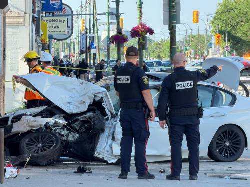 MORGAN MODJESKI / FREE PRESS
                                Officers with the Winnipeg Police Service survey a crumbled white BMW on Main Street on Friday, July 17, 2026. Video captured of the crash indicates that speed may have been a factor in the incident, as two vehicles involved, a motorcycle and the BMW, were travelling at a high rate of speed southbound on Main Street before the collision.