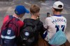 FILE - Three boys use their phones while sitting outside a school in Sydney, Monday, Dec. 8, 2025. (AP Photo/Rick Rycroft, File)