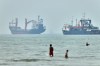 Children wade in the water with cargo ships at anchor in the background and a fisherman nearby, in the Strait of Hormuz off Bandar Abbas, Iran, Tuesday, June 30, 2026. (Amirhosein Khorgooi/ISNA via AP)