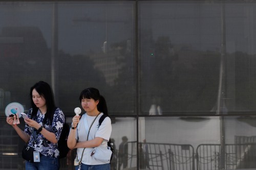 FILE - Visitors use fans as as they wait to enter the Washington Monument, July 1, 2026, in Washington. (AP Photo/Tom Brenner, File)