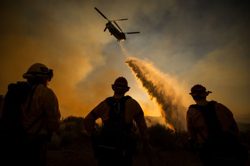 Firefighters watch as a helicopter drops water on the Summit Fire in Llano, CA. Friday, July 10, 2026. (AP Photo/Ethan Swope)