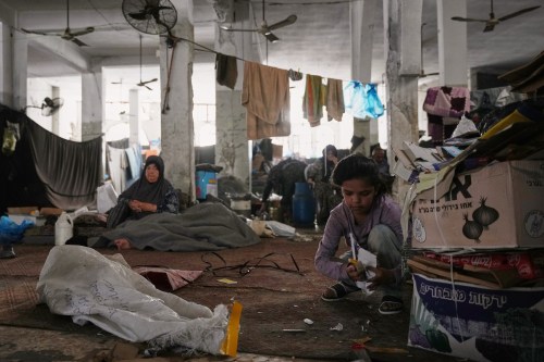 Farah Abu Assi, 12, collects used paper to light a fire for cooking in the hall of Bilal Mosque, which has been converted into a shelter for displaced people, in Khan Younis, southern Gaza Strip, Friday, July 10, 2026. (AP Photo/Abdel Kareem Hana)