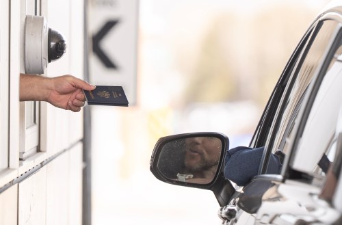 A Canada Border Services officer hands passports back to a visitor entering Canada from Vermont at the Highway 55 Port of Entry in Stanstead, Que., on Thursday, March 13, 2025. THE CANADIAN PRESS/Christinne Muschi