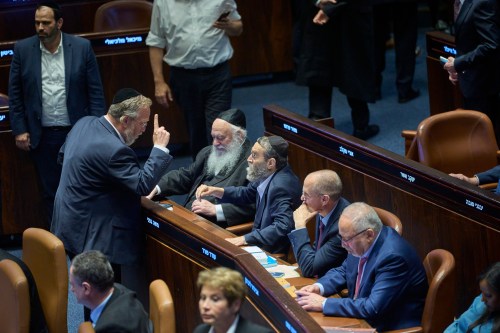 Israeli lawmakers in the Israeli parliament discuss after the vote on a bill that seeks to equate the study of Jewish texts with military service, in Jerusalem, Monday, July 13, 2026. (AP Photo/Ohad Zwigenberg)