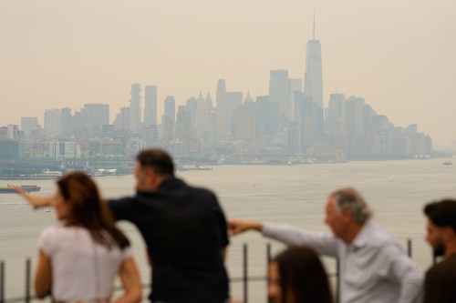 People look over the New York City skyline shrouded in smoke in Weehawken, N.J., Thursday, July 16, 2026. (AP Photo/Seth Wenig)