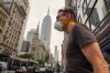 A person wearing a mask walks past the Empire State Building during an air quality health advisory due to wildfire smoke, in New York, Friday, July 17, 2026. (AP Photo/Ryan Murphy)