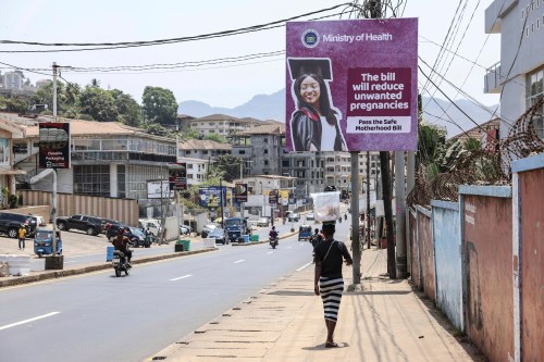 FILE - A woman walks past a billboard promoting the Safe Motherhood Bill on Wilkinson Road in Freetown, Sierra Leone, March 12, 2025. (AP Photo/Caitlin Kelly, File)