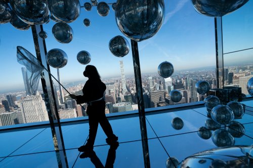 A worker uses a fishing net to circulate a roomful of helium-filled balloons at the grand opening of SUMMIT One Vanderbilt, a skyscraper observatory on Manhattan's iconic 42nd Street, Thursday, Oct. 21, 2021, in New York. (AP Photo/John Minchillo)