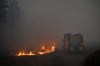 A fire engine drives through smoke of a wildfire raging near Marcheprime, outside, Bordeaux, France, Sunday, July 26, 2026. (AP Photo/Emma Da Silva)