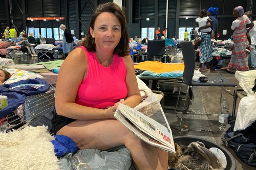 Morgane Bonichot, 40, takes a break from reading a newspaper in an evacuation center in Bordeaux, on Tuesday, July 28, 2026, where she, her daughter, their rabbit and dog are sheltering from wildfires in southwest France. (AP Photo/Eva van Dam)