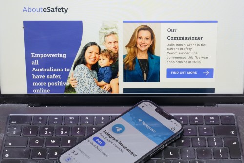 A phone rests on a computer showing the Australian eSafety web page in Sydney, Thursday, July 30, 2026. (AP Photo/Rick Rycroft)