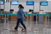 A traveller walks past empty WestJet check-in counters at the Calgary International Airport during the airline's mechanics strike in Calgary, Saturday, June 29, 2024. THE CANADIAN PRESS/Jeff McIntosh