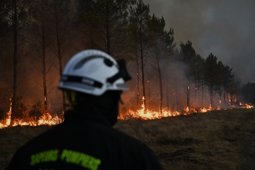 FILE - A firefighter walks in front of burning trees as a wildfire rages near Marcheprime, outside, Bordeaux, France, July 26, 2026. (AP Photo/Emma Da Silva, File)