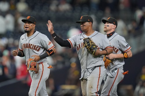San Francisco Giants first baseman Rafael Devers, center, celebrates with teammates second baseman Luis Arraez, left, and third baseman Christian Koss after the Giants defeated the San Diego Padres 4-1 in a baseball game Thursday, July 30, 2026, in San Diego. (AP Photo/Gregory Bull)