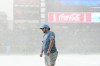 A member of the Coors Field grounds crew stands on the tarpaulin as a storm packing heavy rain and hail sweeps over the stadium before the Colorado Rockies host the Kansas City Royals in a baseball game Friday, July 31, 2026, in Denver. (AP Photo/David Zalubowski)