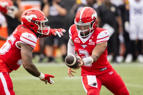 Calgary Stampeders quarterback Vernon Adams Jr. (3) hands the ball off to teammate Dedrick Mills (26) during first half CFL action against the Hamilton Tiger-Cats, in Hamilton, Saturday, Aug. 1, 2026. THE CANADIAN PRESS/Nick Iwanyshyn