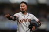 San Francisco Giants' Luis Arraez jokes with players in the San Diego Padres dugout as he stands on first base after getting hit by a pitch during the fourth inning of a baseball game Thursday, July 30, 2026, in San Diego. (AP Photo/Gregory Bull)
