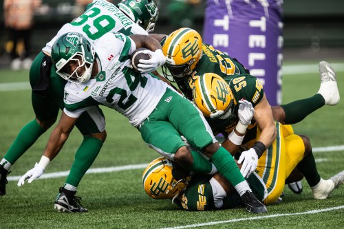 Saskatchewan Roughriders' Quali Conley (24) is tackled by Edmonton Elks' Dariel Djabome (45), Joel Dublanko (50) and Chelen Garnes (25) during first half CFL action in Edmonton on Saturday, Aug. 1, 2026. THE CANADIAN PRESS/Codie McLachlan