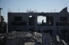 A Palestinian woman inspects a destroyed building following an Israeli airstrike in Deir al-Balah, central Gaza Strip, Sunday, July 19, 2026. (AP Photo/Abdel Kareem Hana)