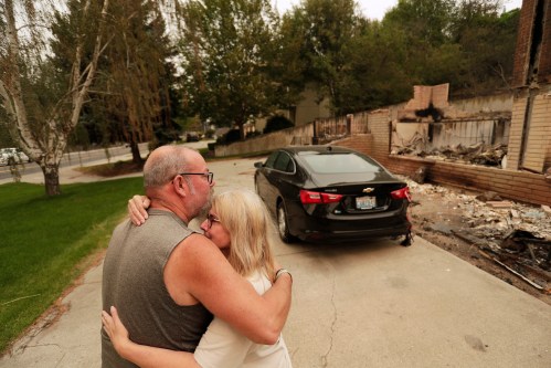 Allen Sather and his wife Kimberley embrace at the duplex they rent on W. Indian Trail Rd. after it burned in a wildfire in Spokane, Wash., Sunday, Aug. 2, 2026. (AP Photo/Young Kwak)