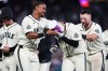 Seattle Mariners' Julio Rodríguez, left, puts a gum bucket on the head of teammate Colt Emerson as they celebrate Emerson's walk-off RBI single during the ninth inning for a win over the Minnesota Twins in a baseball game, Sunday, Aug. 2, 2026, in Seattle. (AP Photo/Lindsey Wasson)