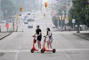People cross Elgin Street on rental e-scooters in Ottawa, on Sunday, June 25, 2023. THE CANADIAN PRESS/Justin Tang