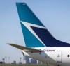 The tail of a WestJet plane is seen dwarfing the Calgary skyline before the airline's annual meeting in Calgary, Tuesday, May 3, 2016. The Transportation Safety Board says an onboard fire that forced a WestJet plane to return to the Calgary International Airport soon after takeoff last June was caused by spare e-cigarette lithium-ion batteries that a passenger failed to declare in his checked baggage. THE CANADIAN PRESS/Jeff McIntosh