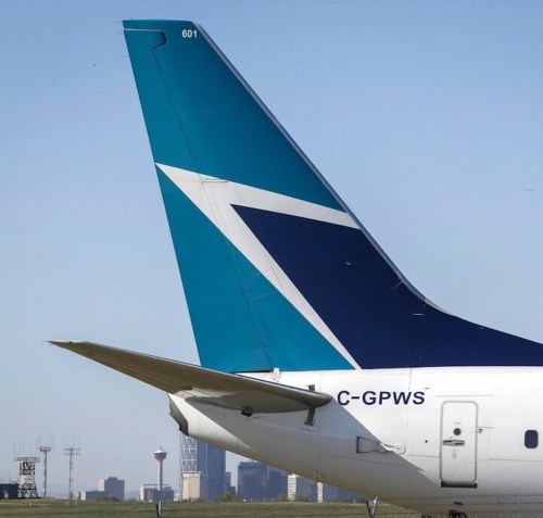 The tail of a WestJet plane is seen dwarfing the Calgary skyline before the airline's annual meeting in Calgary, Tuesday, May 3, 2016. The Transportation Safety Board says an onboard fire that forced a WestJet plane to return to the Calgary International Airport soon after takeoff last June was caused by spare e-cigarette lithium-ion batteries that a passenger failed to declare in his checked baggage. THE CANADIAN PRESS/Jeff McIntosh