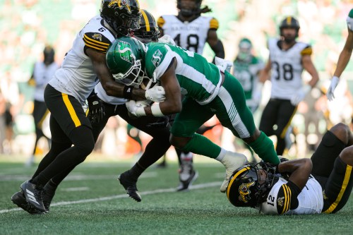 Saskatchewan Roughriders Samuel Emilus (19) fights for a first down against Hamilton Tiger-Cats' Zamari Walton (6) during first half CFL football action in Regina, Sunday, July 12, 2026. THE CANADIAN PRESS/Derek Elvin