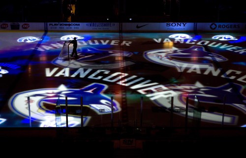 A worker moves a hockey net as Vancouver Canucks team logos are projected on the ice before the team's NHL hockey game against the Detroit Red Wings in Vancouver, B.C., on Thursday Feb. 2, 2012. THE CANADIAN PRESS/Darryl Dyck