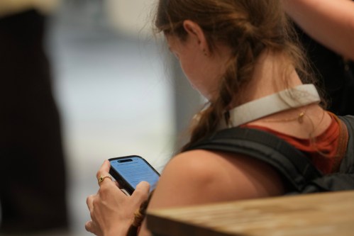 A teenager looks at her mobile phone in London, Monday, June 15, 2026. (AP Photo/Kin Cheung)
