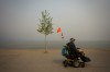 A man using a wheelchair wears a mask due to poor air quality as smoke from the Bald Range wildfire envelops Okanagan Lake, in Penticton, B.C., on Sunday, Aug. 9, 2026. THE CANADIAN PRESS/Darryl Dyck