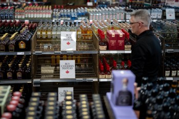 A liquor store employee looks at a sign placed in  the American whiskey section at a B.C. Liquor Store after top selling American made products have been removed from shelves in Vancouver, B.C., Sunday, Feb. 2, 2025. THE CANADIAN PRESS/Ethan Cairns