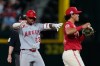 Los Angeles Angels' Denzer Guzman (23) celebrates his run-scoring double in front of Texas Rangers second baseman Nicky Lopez as umpire Alex Tosi, rear, looks on in the 10th inning of a baseball game Friday, Aug. 21, 2026, in Arlington, Texas. (AP Photo/Tony Gutierrez)