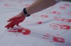 FILE - People cover a sheet in handprints at an event marking Red Hand Day, also known as the International Day against the Use of Child Soldiers, in Bogota, Colombia, where illegal armed groups recruit children, Feb. 12, 2026. (AP Photo/Fernando Vergara, File)