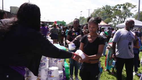 In this photo taken from video, an attendee receives toilet paper from a volunteer at a free community relief event for those struggling after a nearly two-week long power outage in Gary, Ind., Aug. 24, 2026. (AP Photo/Laura Bargfeld)