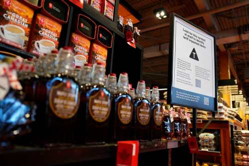 A sign advising that products from the U.S. affected by a tariff will be marked with a symbol at the shelf, along with a QR code linking to a Government of Canada website, is seen beside a display of Canadian products in a grocery store in Ottawa, on Wednesday, April 2, 2025. THE CANADIAN PRESS/Justin Tang