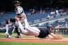 Washington Nationals' Dylan Crews, front, slides home to score on a sacrifice fly by Brady House during the first inning of a baseball game as Colorado Rockies catcher Brett Sullivan waits for the throw, Thursday, Aug. 27, 2026, in Washington. (AP Photo/Nick Wass)