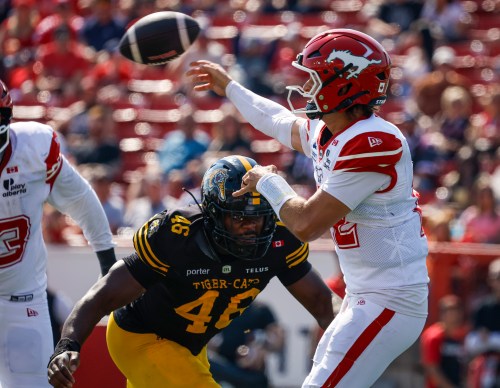 Hamilton Tiger-Cats' Philip Ossai, left, charges Stampeders quarterback Josh Love during second half CFL action in Calgary on Aug. 29, 2026. THE CANADIAN PRESS/Jeff McIntosh