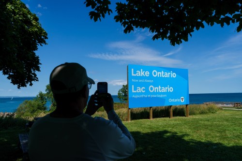 A person takes a picture of the new sign for Lake Ontario at Fifty Point Conservation Area in Grimsby, Ont., on Saturday, Aug. 29, 2026. THE CANADIAN PRESS/Keito Newman