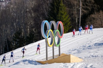 FILE - Athletes ski past the Olympic rings during the cross country skiing women's 50km mass start classic at the 2026 Winter Olympics, in Tesero, Italy, Feb. 22, 2026. (AP Photo/Matthias Schrader, File)