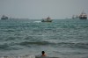 A swimmer remains near the shore as a motorboat passes commercial vessels anchored in the Strait of Hormuz off Bandar Abbas, Iran, Friday, Sept. 4, 2026. (AP Photo/Vahid Salemi)