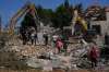 People watch rescue workers use excavators as they search for victims under the rubble of a building destroyed in an Israeli airstrike in the southern village of Kfar Rumman, Lebanon, Monday, Sept. 7, 2026. (AP Photo/Mohammed Zaatari)
