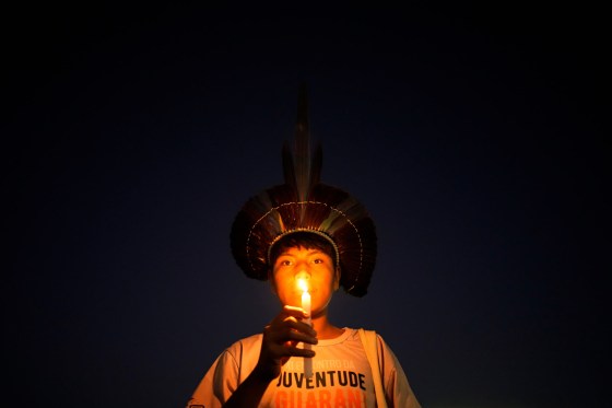 An Indigenous youth holds a candle during a protest calling for the protection of Indigenous land rights and demarcations outside the Supreme Court in Brasilia, Brazil, last Tuesday. (Eraldo Peres / The Associated Press)